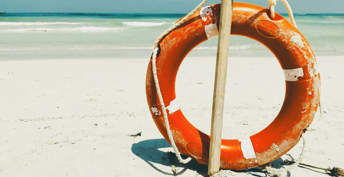 Lifebuoy resting on the sand of an empty beach